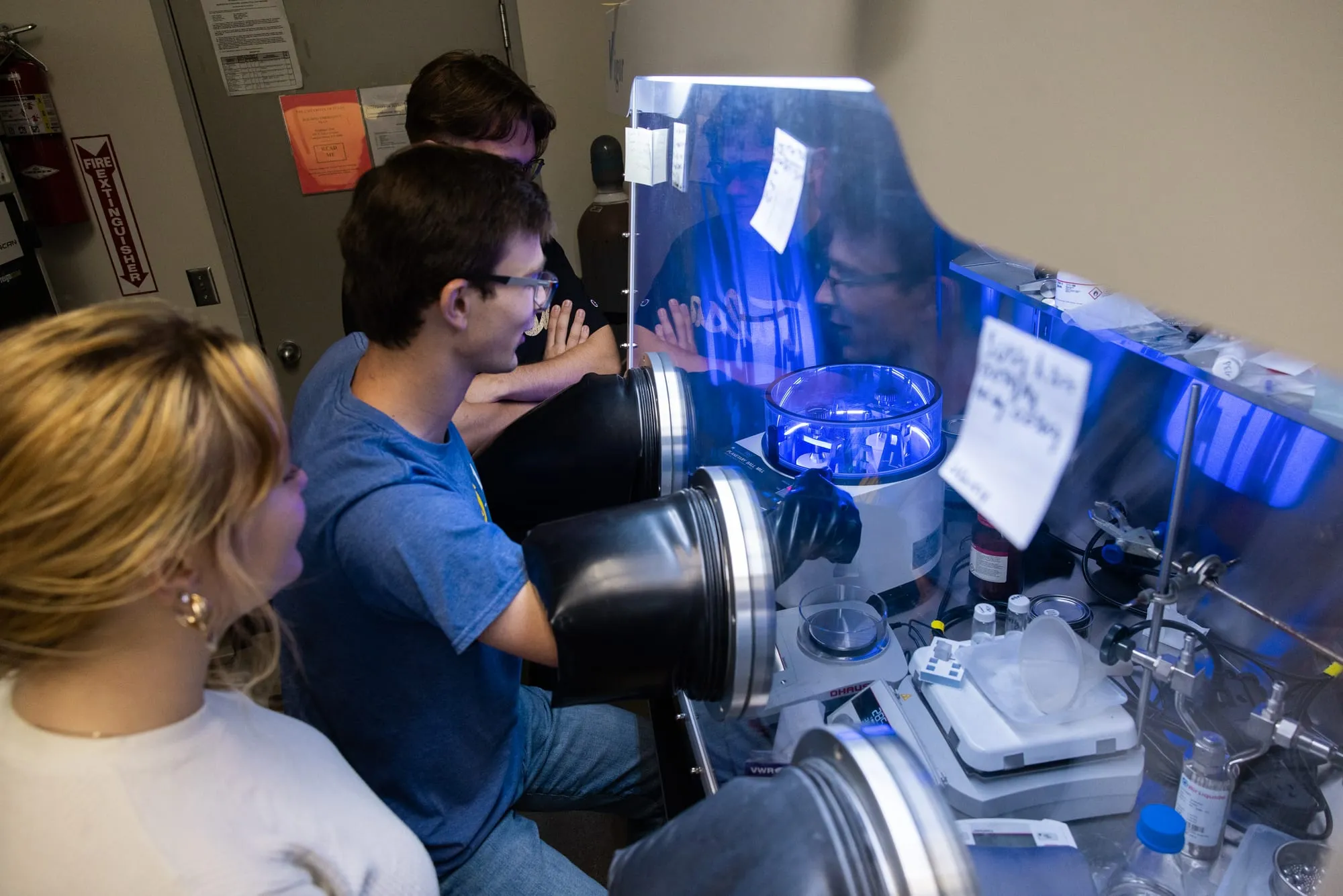 AMDG members working at the Vigor 2G argon glovebox, with one member reaching into the gloves to handle a sample.