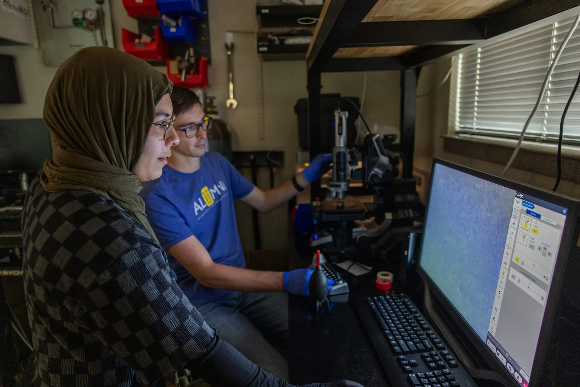 Two students inspect a micrograph on the Keyence digital microscope display.